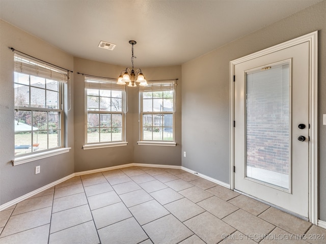 unfurnished dining area with a notable chandelier and light tile patterned floors