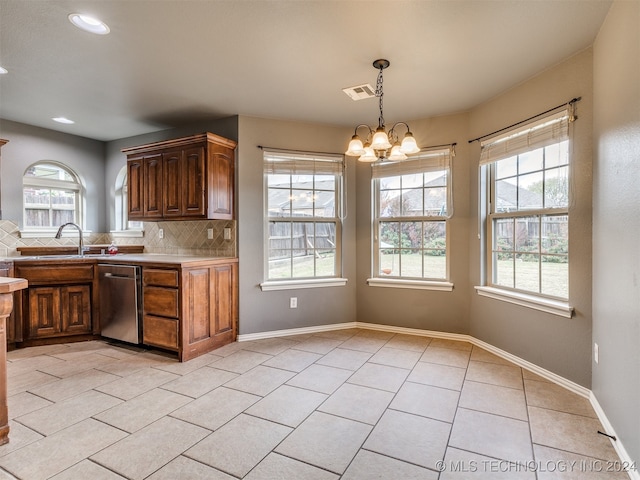 kitchen with backsplash, a chandelier, plenty of natural light, and stainless steel dishwasher