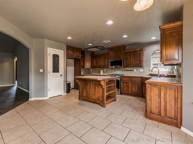 kitchen featuring a center island, sink, light wood-type flooring, tasteful backsplash, and stainless steel appliances