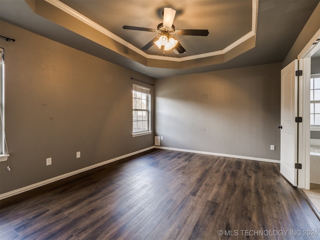 spare room with ceiling fan, dark hardwood / wood-style flooring, ornamental molding, and a tray ceiling