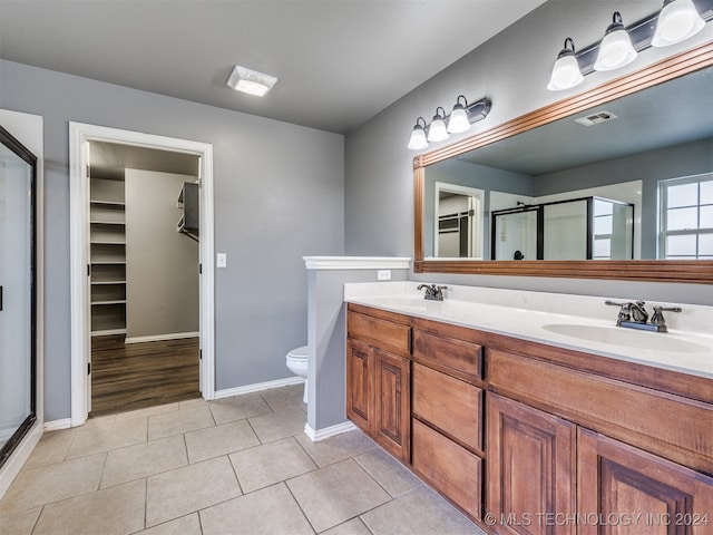 bathroom with toilet, vanity, tile patterned floors, and an enclosed shower