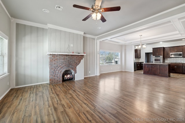 unfurnished living room featuring a brick fireplace, hardwood / wood-style flooring, ceiling fan with notable chandelier, and ornamental molding