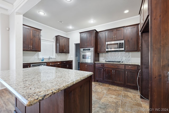 kitchen featuring sink, appliances with stainless steel finishes, dark brown cabinetry, light stone counters, and ornamental molding