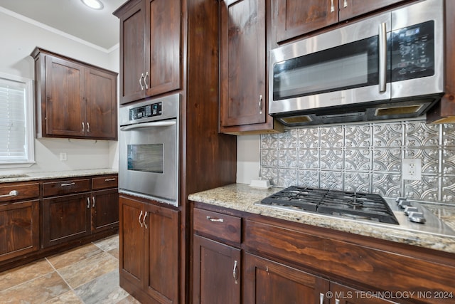 kitchen featuring backsplash, ornamental molding, dark brown cabinetry, stainless steel appliances, and light stone countertops