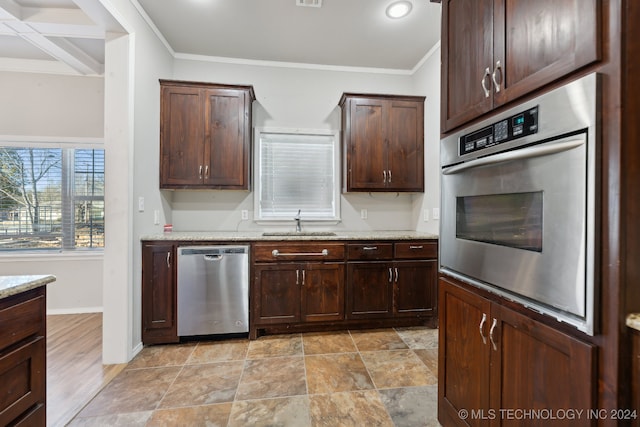 kitchen with stainless steel appliances, light stone countertops, sink, and dark brown cabinets