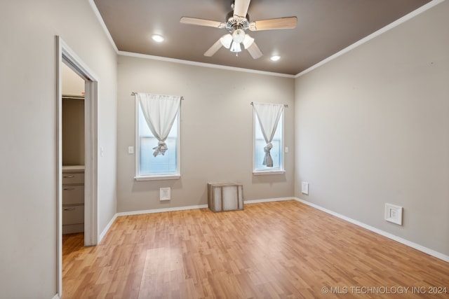 unfurnished bedroom featuring crown molding, a spacious closet, light hardwood / wood-style flooring, a closet, and ceiling fan