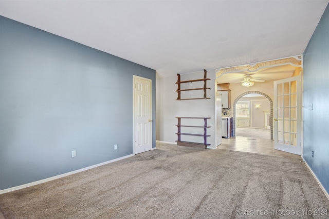 carpeted spare room with ceiling fan and french doors