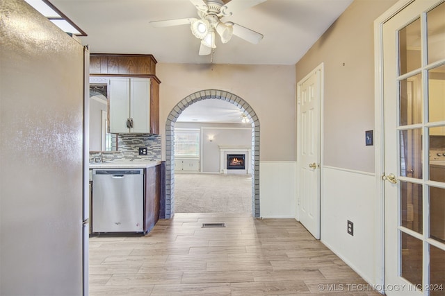 kitchen featuring backsplash, ceiling fan, dishwasher, and light wood-type flooring