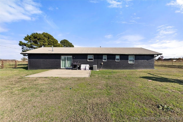 rear view of property with cooling unit, a patio area, and a yard