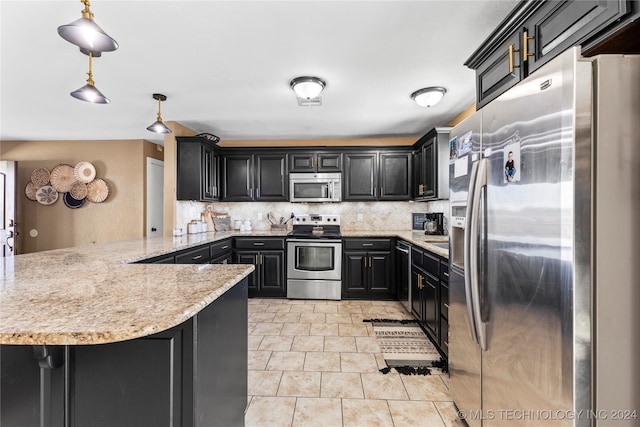 kitchen with kitchen peninsula, appliances with stainless steel finishes, backsplash, a breakfast bar, and decorative light fixtures