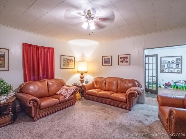 carpeted living room with ceiling fan and ornamental molding