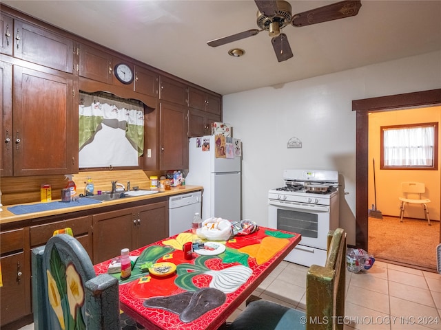 kitchen featuring dark brown cabinets, white appliances, sink, and light tile patterned floors