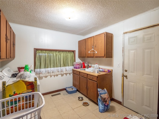 laundry area featuring washer and clothes dryer, wood walls, cabinets, a textured ceiling, and light tile patterned flooring