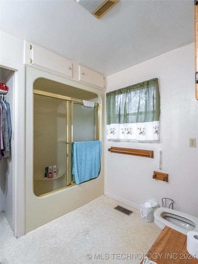 bathroom featuring shower / bath combination with glass door and toilet