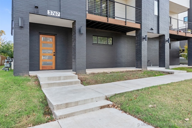 entrance to property with a lawn and a balcony