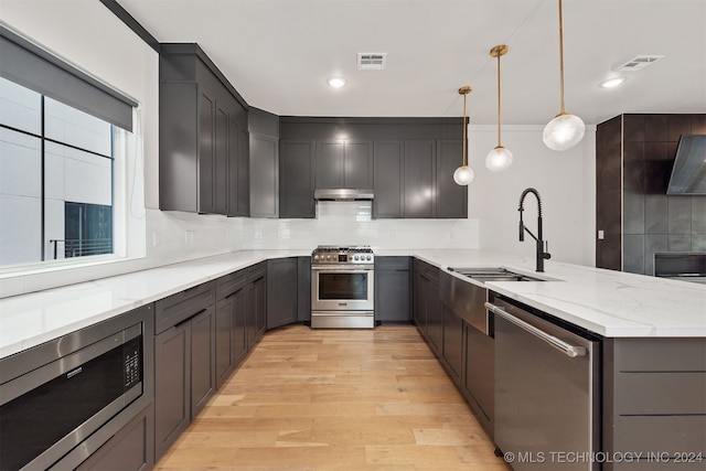 kitchen with pendant lighting, decorative backsplash, sink, and stainless steel appliances