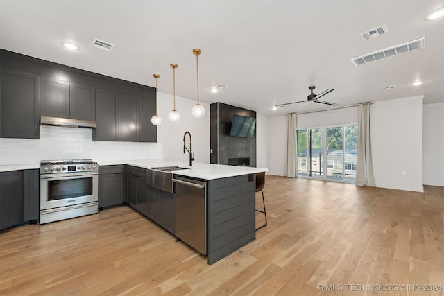 kitchen with kitchen peninsula, decorative light fixtures, stainless steel appliances, and light hardwood / wood-style flooring