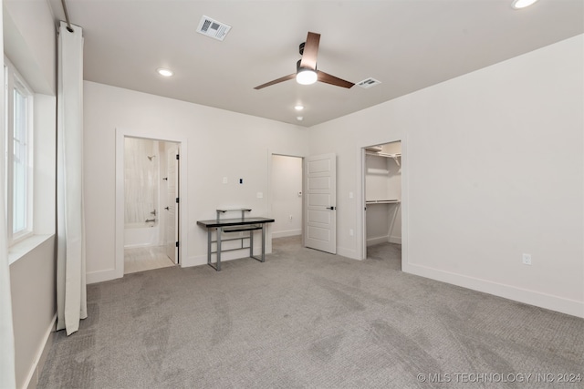 unfurnished bedroom with ceiling fan, light colored carpet, a spacious closet, and a closet