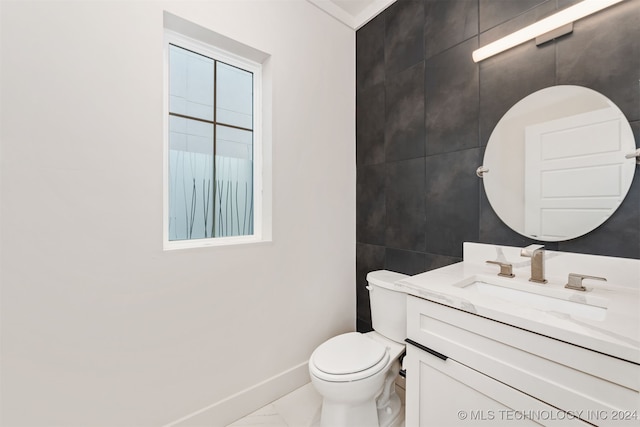 bathroom featuring vanity, tile walls, and toilet