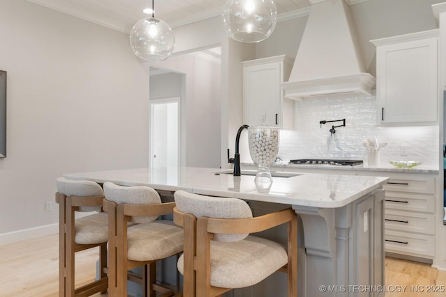 3908 S Elder Blvd, Broken Arrow, OK 74012 - kitchen with custom range hood, ornamental molding, backsplash, an island with sink, and light wood-style flooring
