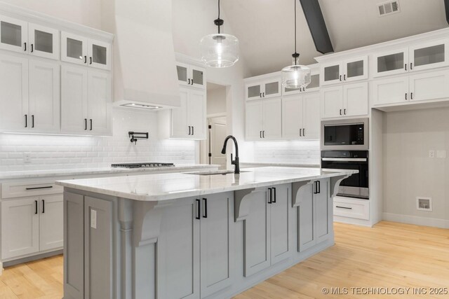 6617 S Fir Ave, Broken Arrow, OK 74134 - kitchen with stainless steel appliances, a sink, custom exhaust hood, decorative backsplash, and light wood-style flooring