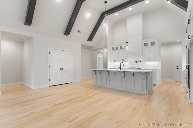 6617 S Fir Ave, Broken Arrow, OK 74134 - kitchen with high vaulted ceiling, a large island with sink, light countertops, white cabinets, and tasteful backsplash