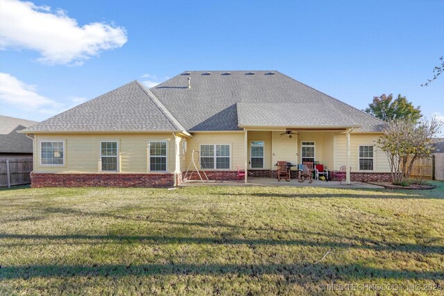 rear view of house featuring ceiling fan, a patio area, and a lawn