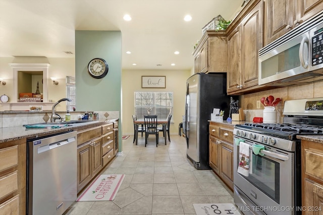 kitchen with light stone counters, light tile patterned floors, backsplash, and appliances with stainless steel finishes