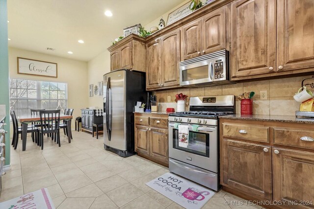 kitchen with light tile patterned flooring, stainless steel appliances, and decorative backsplash