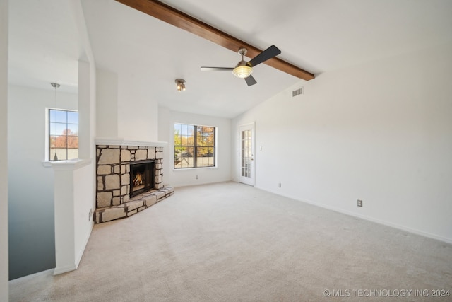 unfurnished living room featuring vaulted ceiling with beams, ceiling fan, a stone fireplace, and light carpet