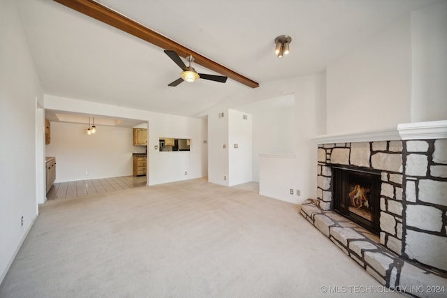 living room with ceiling fan, a stone fireplace, light colored carpet, and lofted ceiling with beams