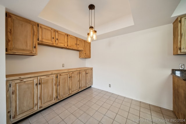 kitchen with decorative light fixtures, a tray ceiling, and light tile patterned floors