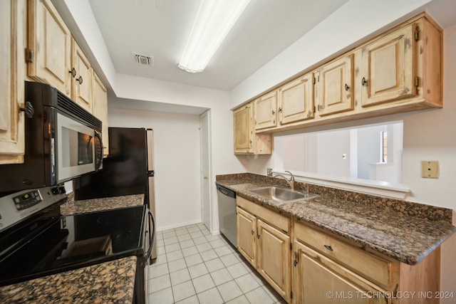 kitchen featuring light brown cabinetry, sink, black appliances, light tile patterned floors, and dark stone countertops