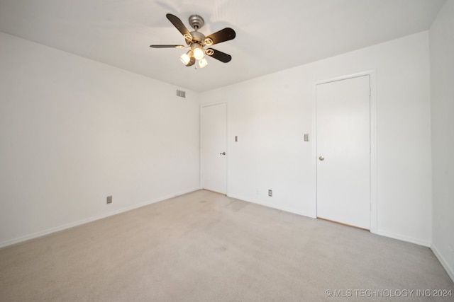 unfurnished bedroom featuring ceiling fan, light colored carpet, and a closet