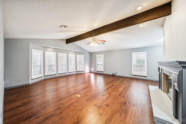 unfurnished living room with a textured ceiling, vaulted ceiling with beams, ceiling fan, a fireplace, and hardwood / wood-style flooring