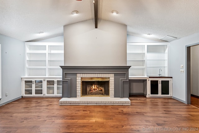 unfurnished living room featuring dark hardwood / wood-style flooring, vaulted ceiling with beams, and a textured ceiling