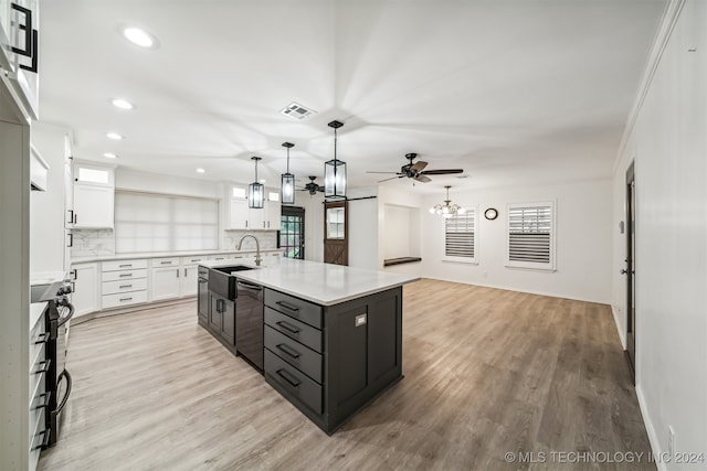 kitchen with stainless steel dishwasher, decorative light fixtures, backsplash, white cabinets, and an island with sink