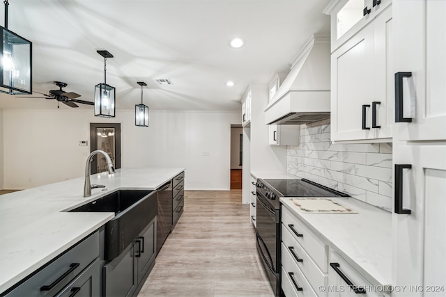 kitchen with light stone countertops, electric range oven, white cabinets, sink, and hanging light fixtures