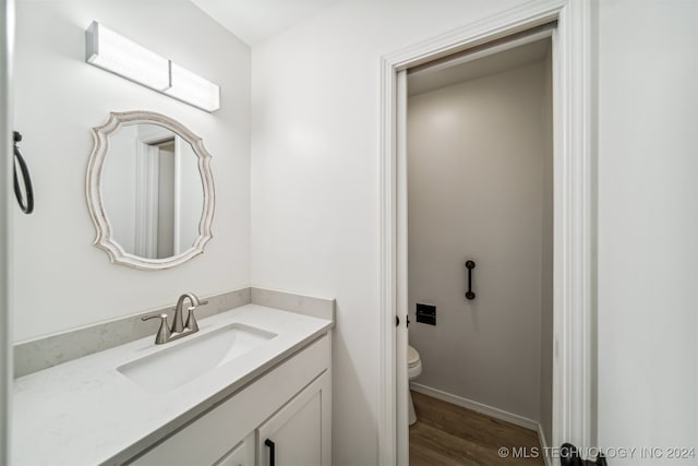 bathroom with hardwood / wood-style floors, toilet, and vanity