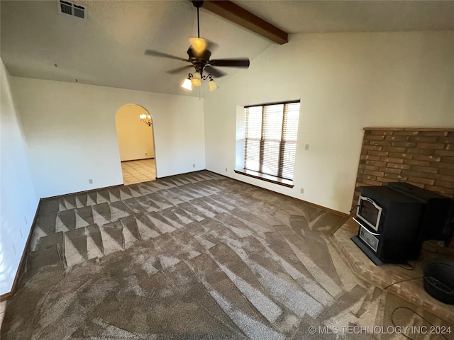 unfurnished living room with a wood stove, ceiling fan, carpet, and lofted ceiling with beams