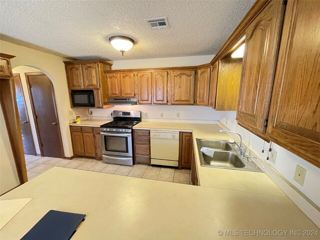 kitchen with white dishwasher, stainless steel gas range oven, sink, and a textured ceiling