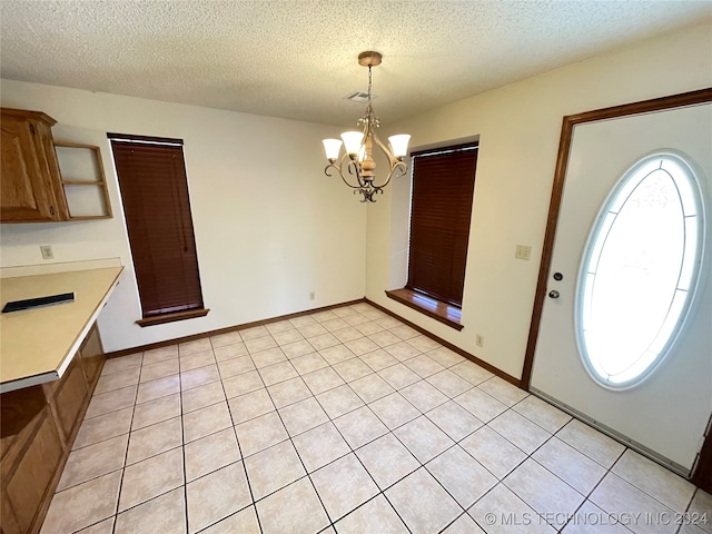 interior space with light tile patterned floors, a chandelier, and a textured ceiling