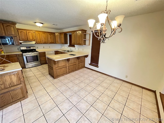 kitchen featuring a textured ceiling, sink, hanging light fixtures, and stainless steel range oven