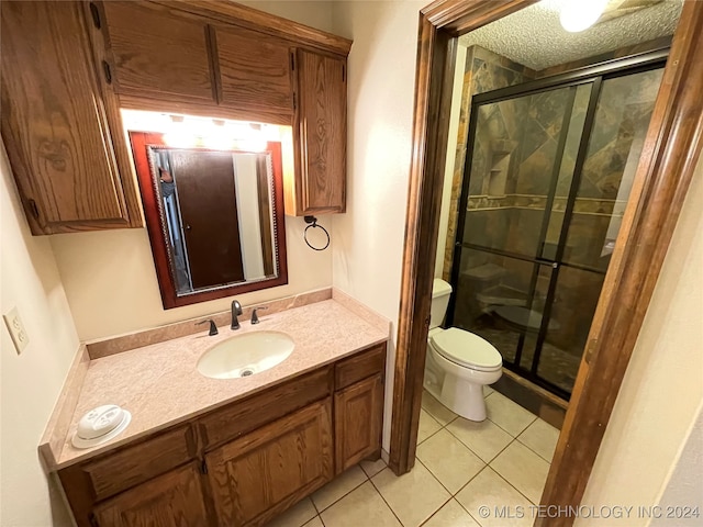 bathroom with tile patterned flooring, a textured ceiling, toilet, vanity, and a shower with shower door