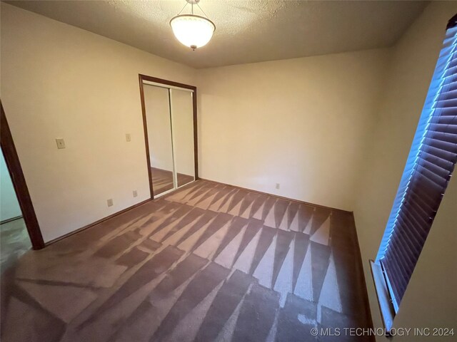 unfurnished bedroom with a closet, carpet, and a textured ceiling