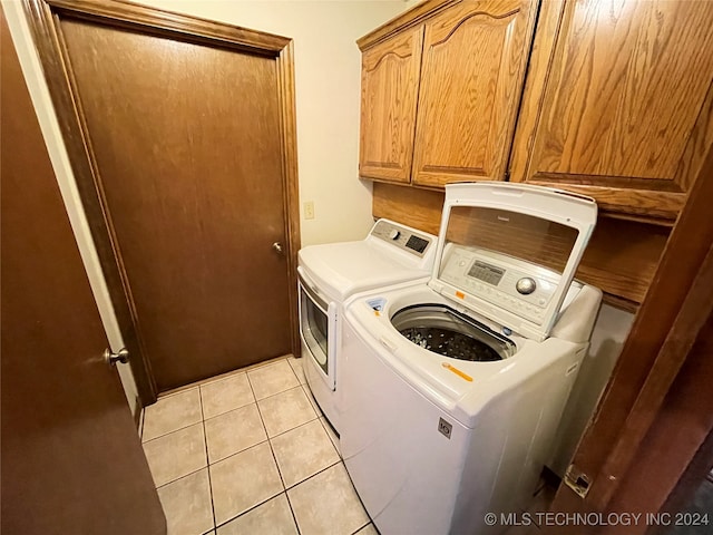 laundry area with washer and clothes dryer, light tile patterned floors, and cabinets