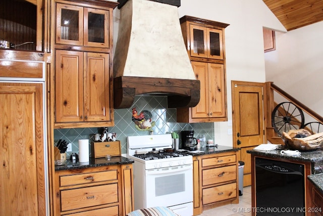 kitchen with white gas range oven, backsplash, dark stone counters, custom range hood, and black dishwasher