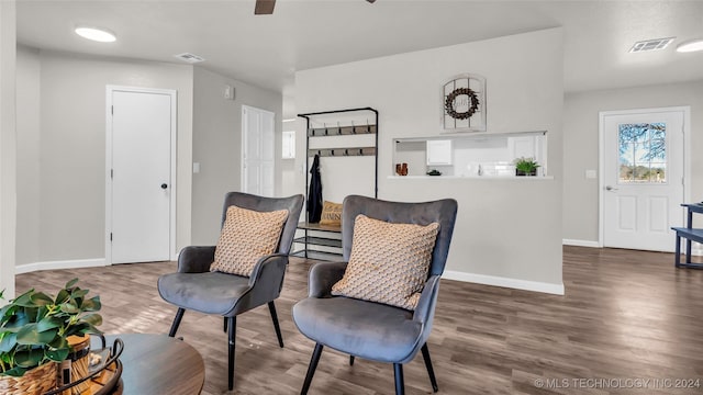 sitting room with ceiling fan and dark wood-type flooring