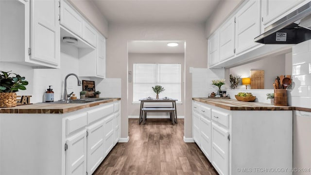 kitchen with dark wood-type flooring, wooden counters, ventilation hood, sink, and white cabinetry