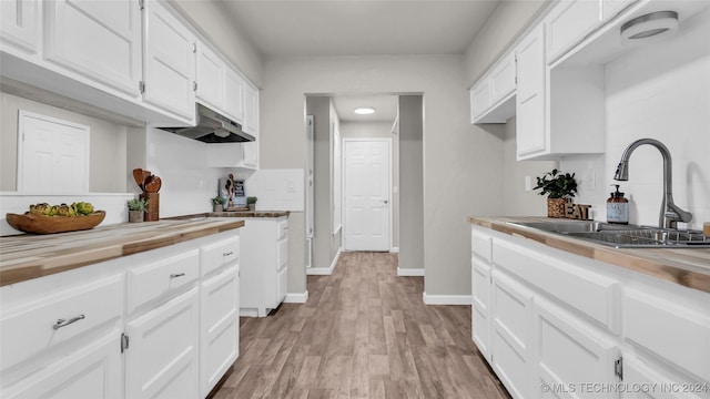 kitchen featuring wood counters, light hardwood / wood-style flooring, white cabinetry, and sink